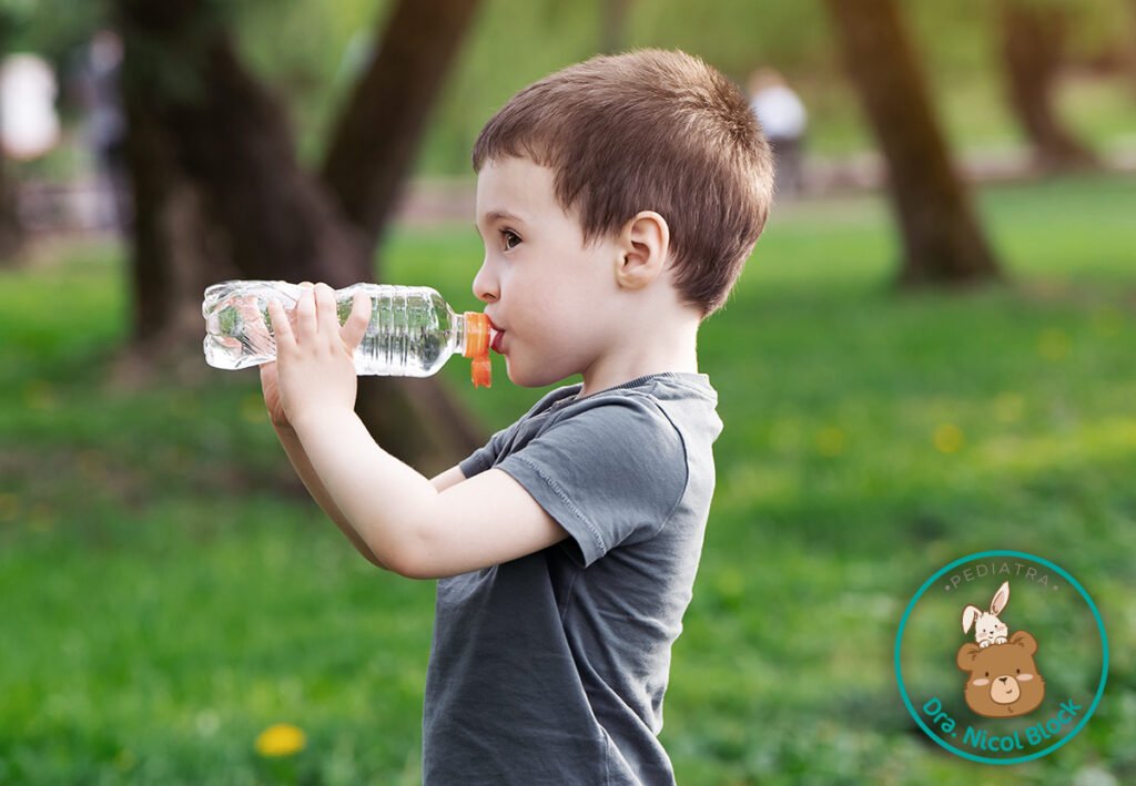 niño tomando agua en una botella para hidratarse.